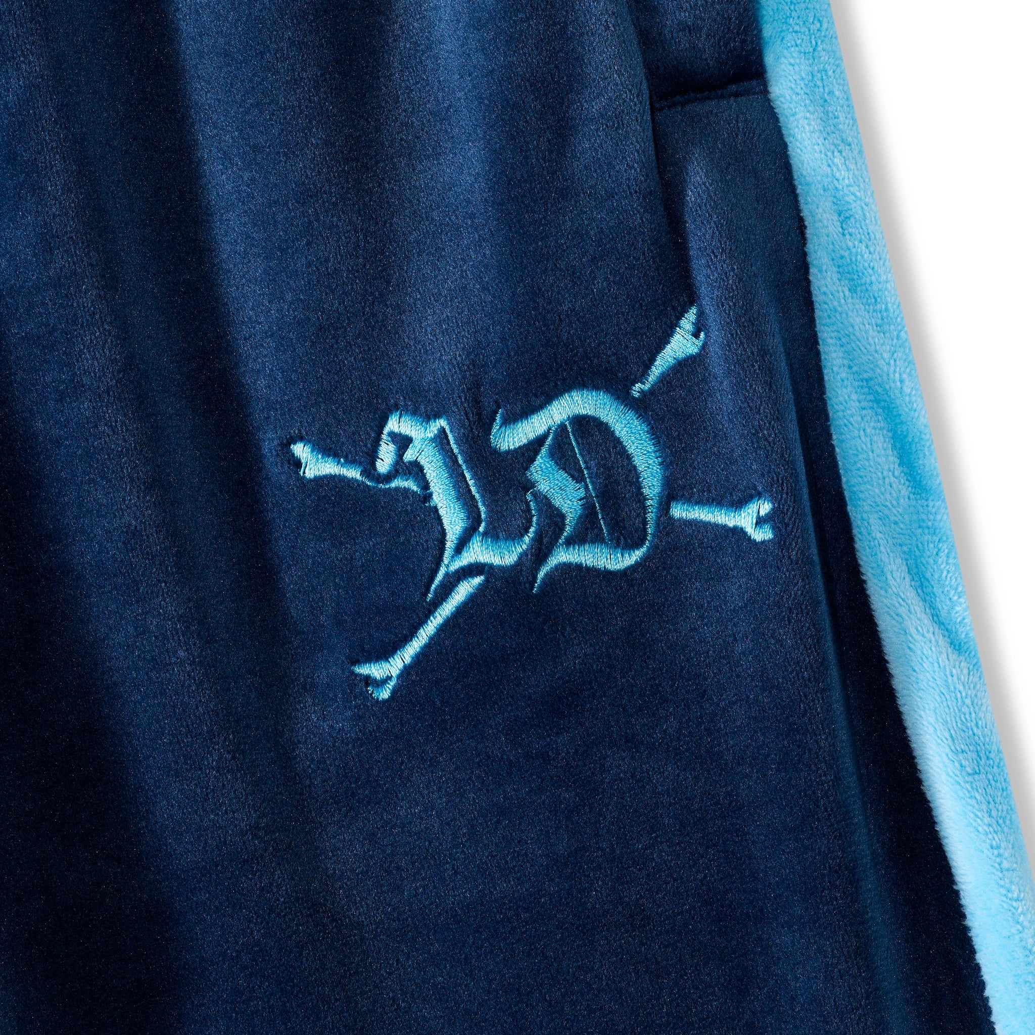 Navy blue fabric with a blue embroidered logo on a white background