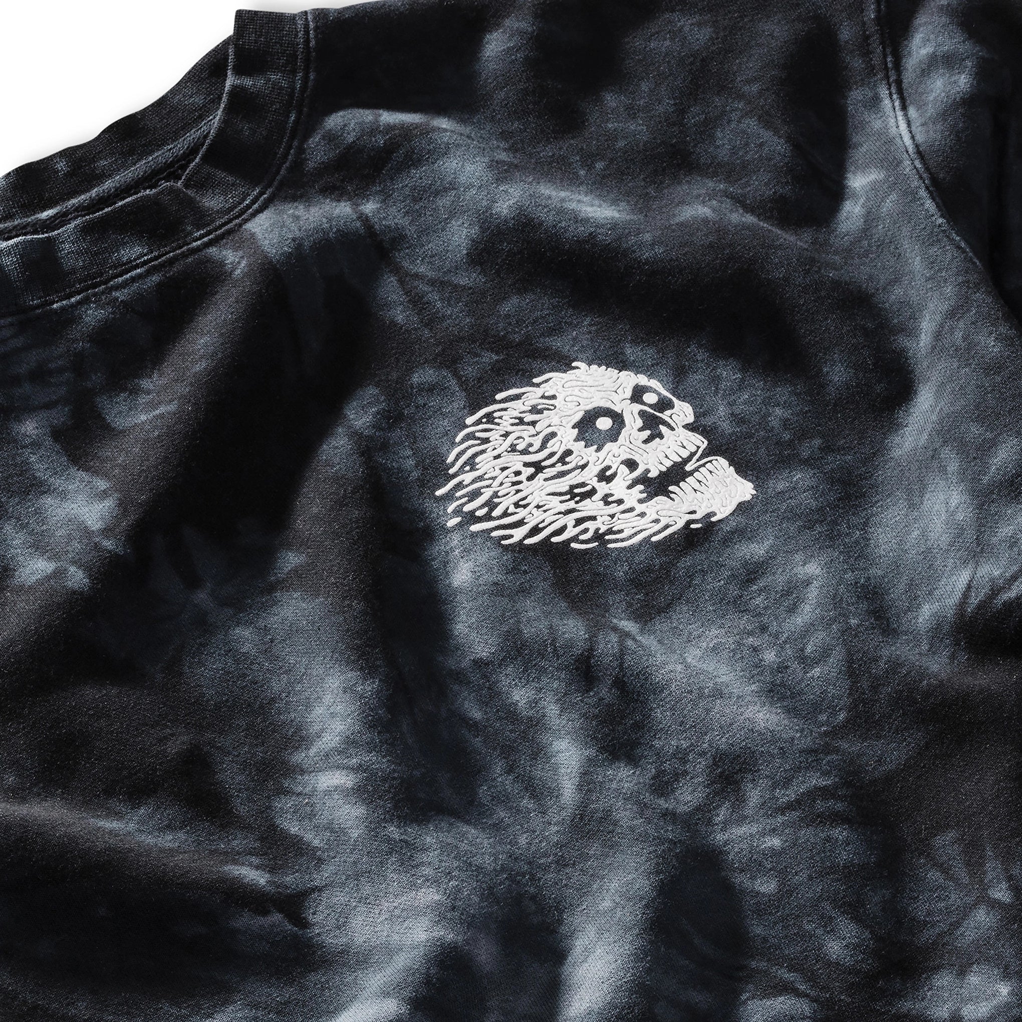 Black tie-dye shirt with a white embroidered design on a plain background