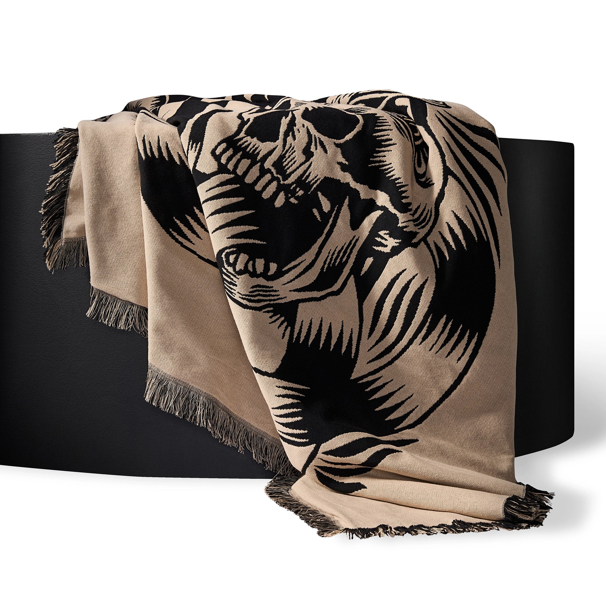 Beige blanket with black elephant design draped over a black surface