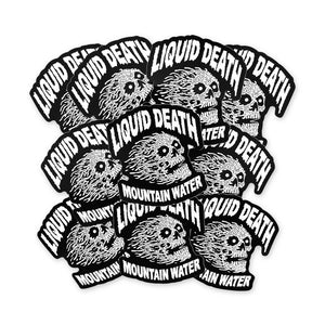 Multiple stickers with 'Liquid Death' and 'Mountain Water' text and skull design on a white background.